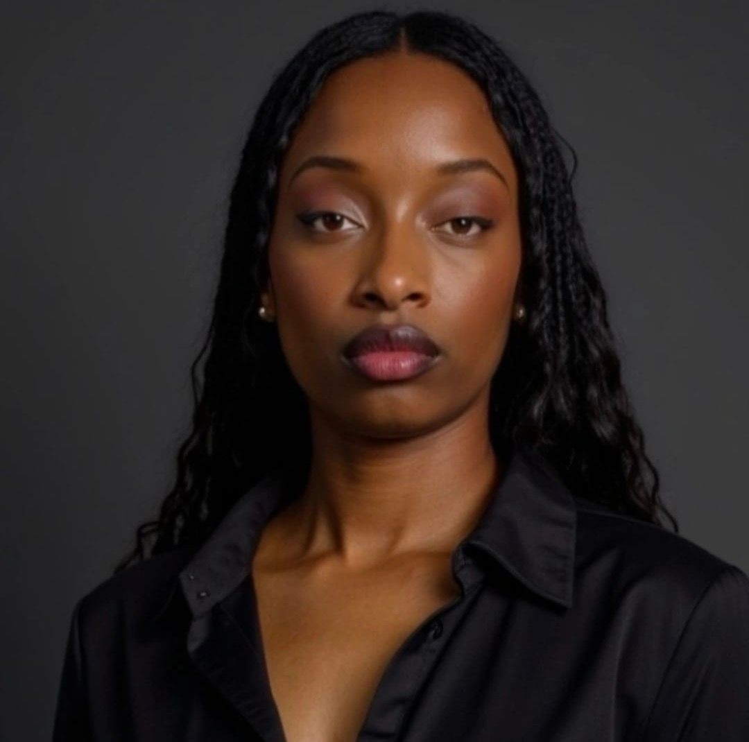 Portrait of a person with long black hair and a black shirt against a dark background.