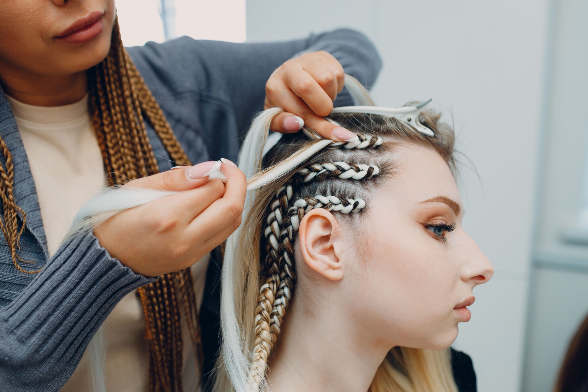 Hairstylist braided afro braids pigtails hair of female client in barber salon