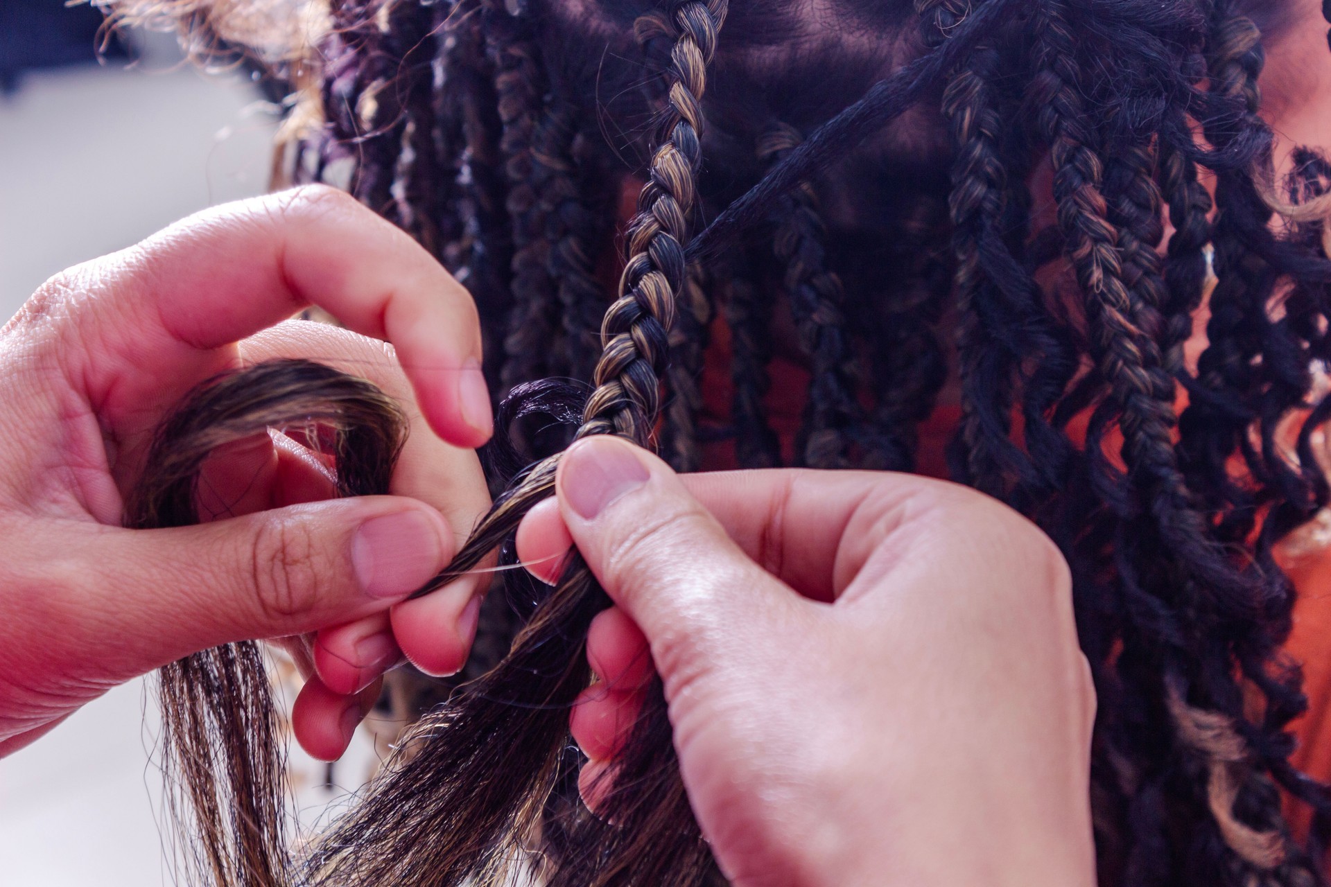 Professional braider stretching hair by applying natural braids