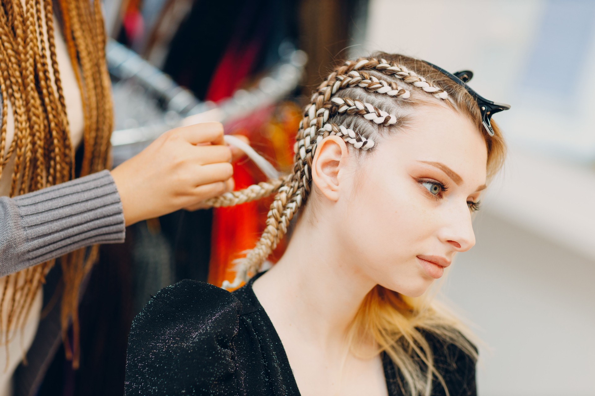 Hairstylist braided afro braids pigtails hair of female client in barber salon